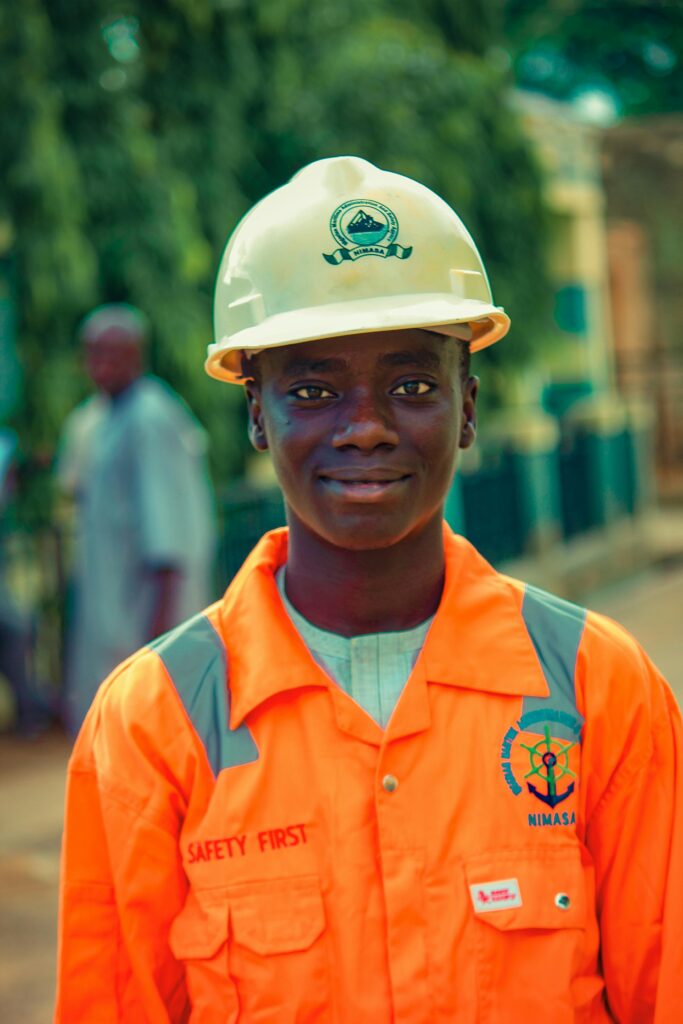 Services A young male worker in safety gear and helmet standing outdoors, emphasizing safety and professionalism.