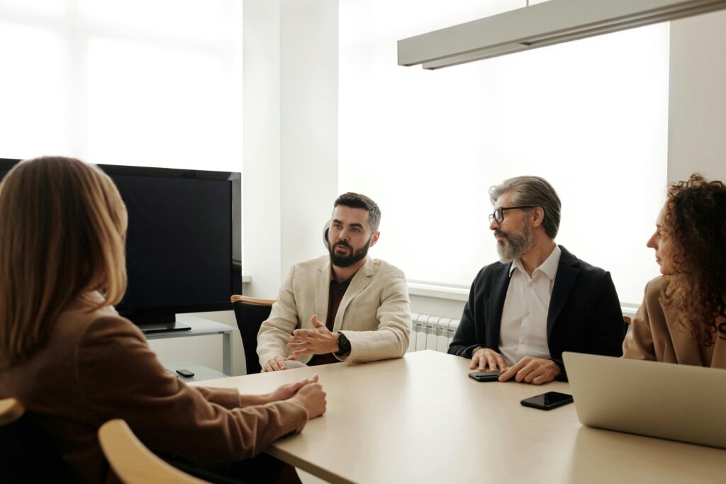 Services A diverse group of business professionals engaged in a meeting in an office setting.