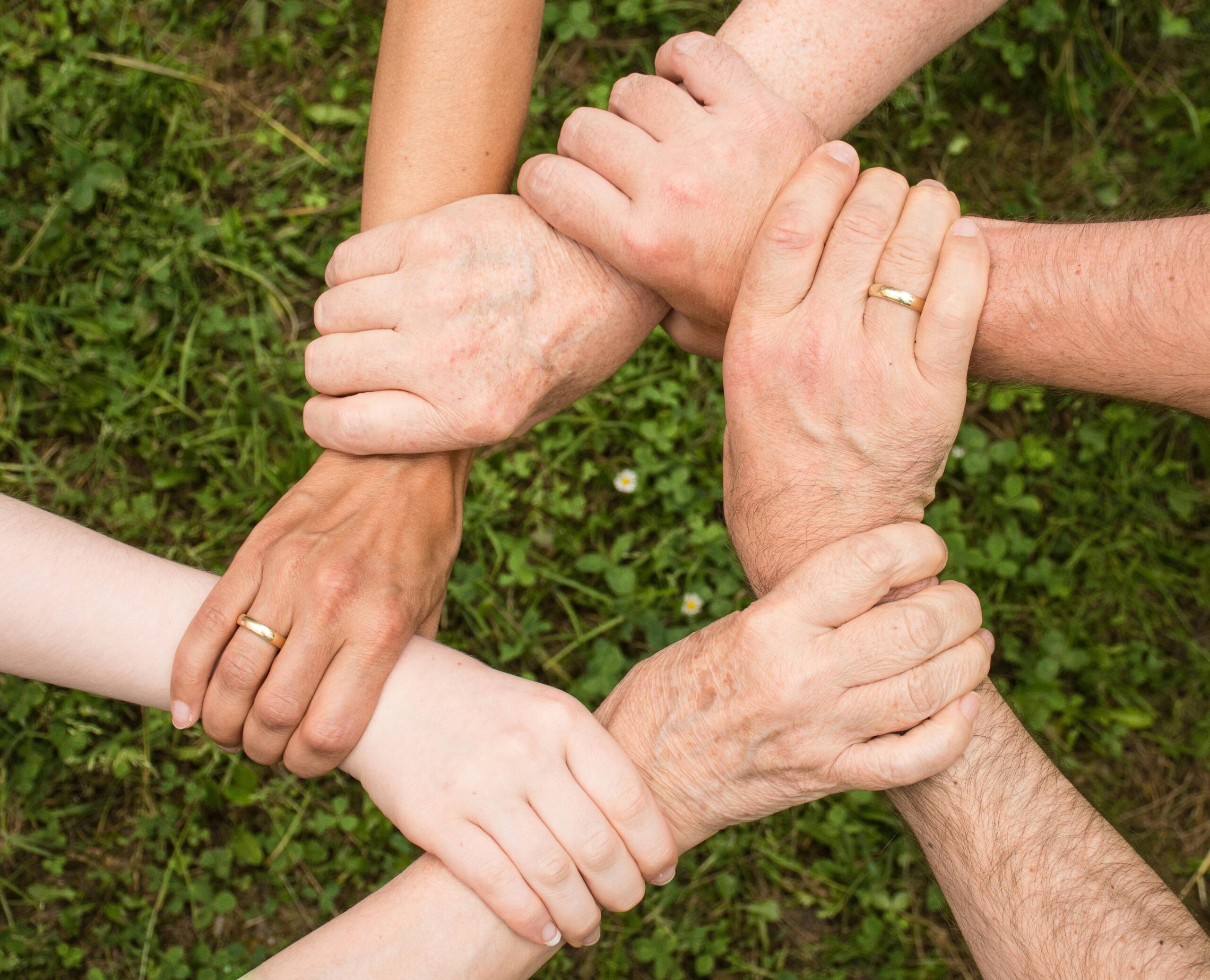 About Close-up of diverse hands forming a connection, symbolizing teamwork and unity outdoors.